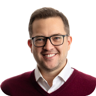 Professional head shot of a man wearing glasses and a red button up smiling at the camera