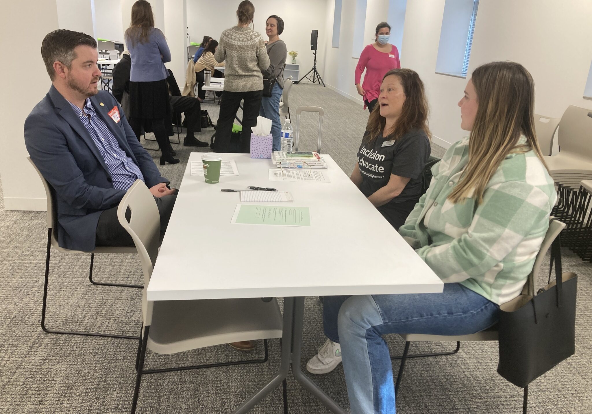 Volunteers sitting with a state representative at a table discussing issues.